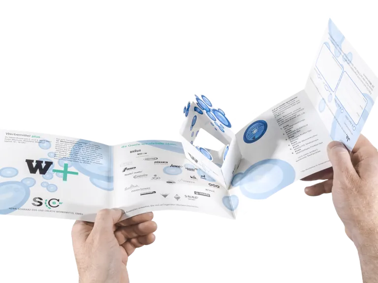 Foto: Person betrachtet die geöffnete Einladungskarte mit der verkleineten Version der W+ Box, die als selbstaufstellendes PopUp-Element integriert ist.