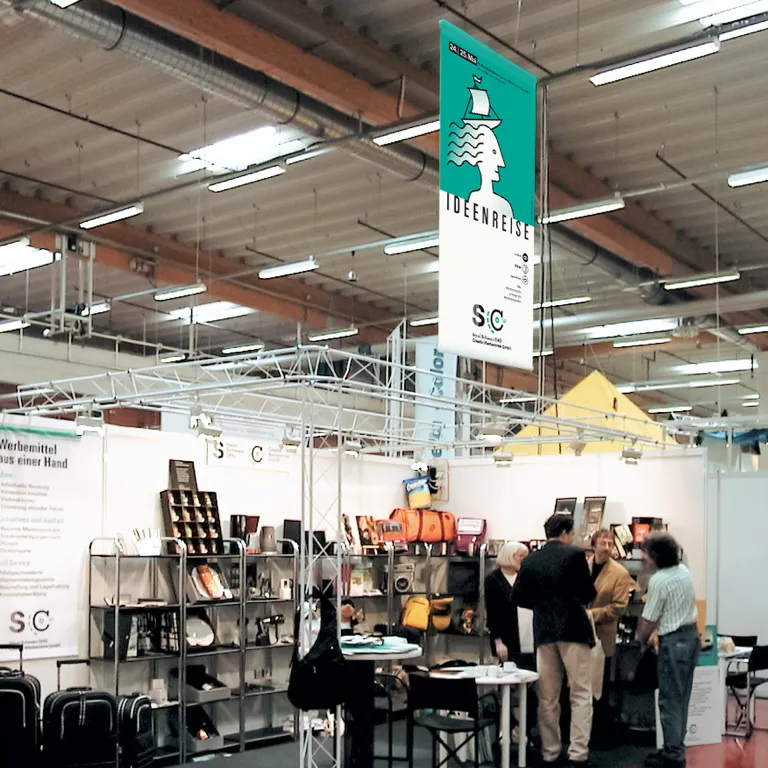 Foto: Werbemittel-Messestand mit von Decke abgehängtem Messebanner, Motiv: Ideenreise